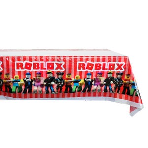 Puede incluir: Un mantel a rayas rojas y blancas con la palabra "ROBLOX" en letras blancas. El mantel presenta un patr&oacute;n repetitivo de personajes de Roblox en una fila a lo largo del borde inferior. Los personajes son de varios colores y poses.