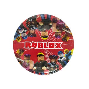 Puede incluir: Un plato de papel rojo redondo con la palabra "ROBLOX" en letras blancas. El plato est&aacute; decorado con personajes de dibujos animados del juego Roblox, en varias poses y atuendos.