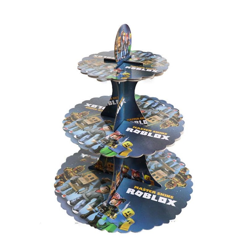 Puede incluir: Un soporte para cupcakes de cart&oacute;n de tres niveles con tem&aacute;tica de Roblox. El soporte tiene una combinaci&oacute;n de colores azul y blanco con personajes de Roblox y las palabras "Master Skins Roblox" impresas en cada nivel. Los bordes de los niveles son festoneados.