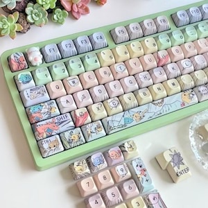 May include: A pastel-colored mechanical keyboard with custom keycaps featuring cartoon characters. The keyboard has a light green frame and a variety of keycap designs, including a bear-shaped key. The Enter key has the word "ENTER" printed on it.