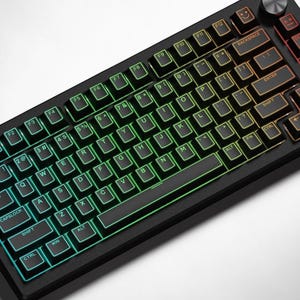 May include: A white ceramic mug with a black handle and the text "But First, Coffee" in a bold, black font. The mug is set against a blurred background, suggesting a cosy setting.