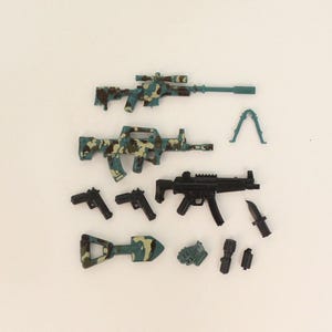 May include: A collection of toy military weapons, including rifles, pistols, and a knife. The rifles feature a camouflage pattern in shades of blue, green, and brown. Additional accessories include a bipod, a shovel, and other small items.