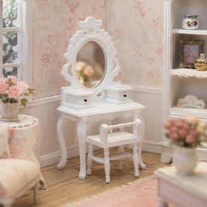 May include: A white miniature vanity table featuring an oval mirror with an ornate frame, two small drawers with black knobs, and curved legs. A matching white stool with four legs and a horizontal backrest is positioned in front of the vanity.