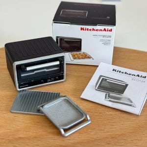 以下が含まれることがあります： エアフライ機能を備えた、ミニチュアのKitchenAidデジタルカウンタートップオーブン。 黒いオーブンはシルバーのハンドルとデジタルディスプレイを備えています。付属品には、シルバーのベーキングトレイとマニュアルが含まれます。 オーブンはオリジナルのパッケージで表示されています。