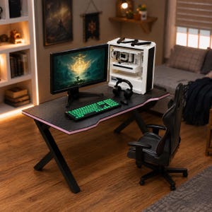 May include: A black gaming desk with an X-shaped base and pink edge lighting, featuring a computer monitor displaying a fantasy landscape, a white PC tower, a mechanical keyboard with green backlit keys, a black headset, and a black gaming chair.