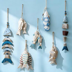 Peut inclure: Plusieurs décorations murales en forme de poissons en bois, suspendues par des cordes naturelles. Les poissons présentent des motifs et des couleurs variés, notamment du bleu, du blanc et des tons bois naturels. Thème nautique sur fond bleu clair.