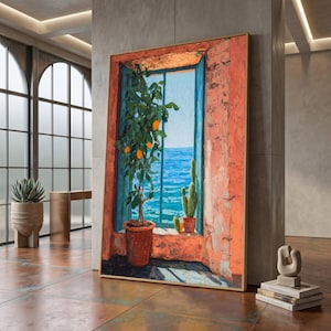 May include: A framed painting depicts a vibrant coastal scene. A potted orange tree sits in a window overlooking the blue ocean. The window frame is painted in shades of orange and red, with a gold frame.