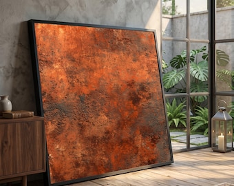 May include: Large abstract art piece with a textured, rusty orange and brown surface, framed in black. The artwork leans against a wall, creating a modern, industrial aesthetic. The room features a wooden floor and a large window.