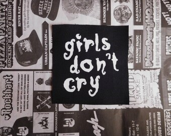 May include: Black and white iron-on patch with the text "girls don't cry" in white lettering on a black background.