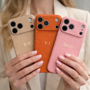 Puede incluir: Se muestran tres fundas de teléfono personalizadas en beige, naranja y rosa. Cada funda presenta un acabado texturizado y unas iniciales únicas: R.W, P.J y S.D. Las fundas tienen un recorte para la cámara.