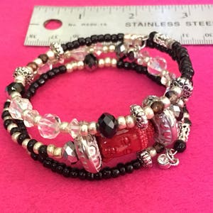 Red buddha, faceted onyx rondelle, black seed beads, silver bead spacers, clear bead, wire adjustable bracelet