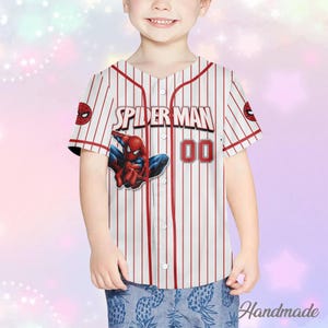 May include: White and red striped baseball jersey featuring the words "SPIDER MAN" and the number "00" in red. The jersey has a Spider-Man graphic on the front. The jersey has short sleeves and a button-up front.