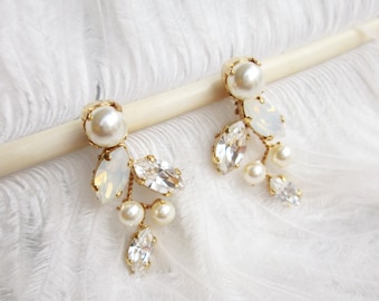 May include: A pair of gold earrings with white pearl accents and clear crystal embellishments. The earrings feature a delicate, cascading design with multiple small pearls and crystals.