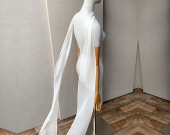 May include: A white sheer scarf draped over a white mannequin. The scarf is long and flowing, and it is made of a lightweight fabric.