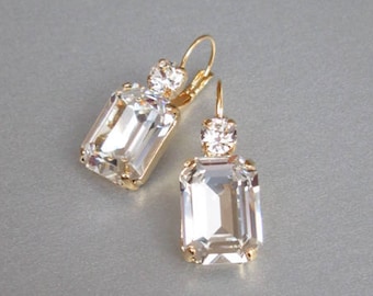 May include: A pair of gold earrings with clear emerald-cut crystal stones. The earrings have a simple design and are perfect for everyday wear.
