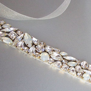 May include: A white satin ribbon with a row of clear and iridescent rhinestones, perfect for adding a touch of sparkle to a wedding dress or special occasion outfit.