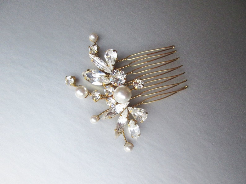 Puede incluir: Un peine de pelo dorado con un dise&ntilde;o floral con pedrer&iacute;a transparente y perlas blancas.