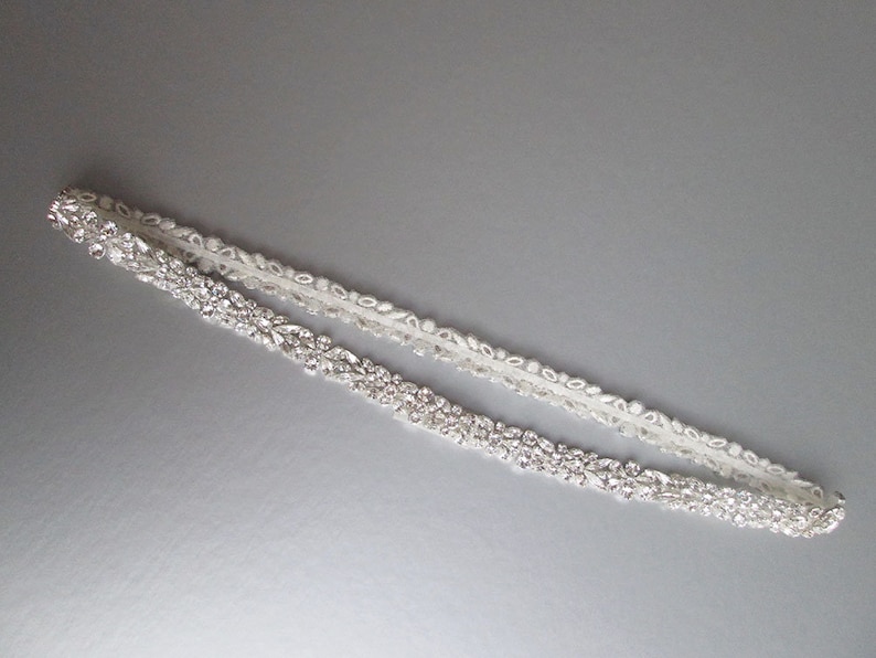 May include: A white satin bridal sash with a beaded design featuring clear rhinestones.