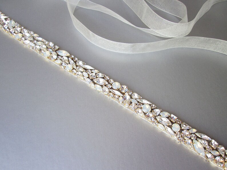 May include: A delicate white satin ribbon with a row of clear and iridescent rhinestones, perfect for adding a touch of sparkle to a wedding dress or special occasion outfit.