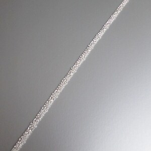 May include: A silver beaded trim with a clear backing. The trim is approximately 76 cm long and is perfect for adding a touch of sparkle to any project.