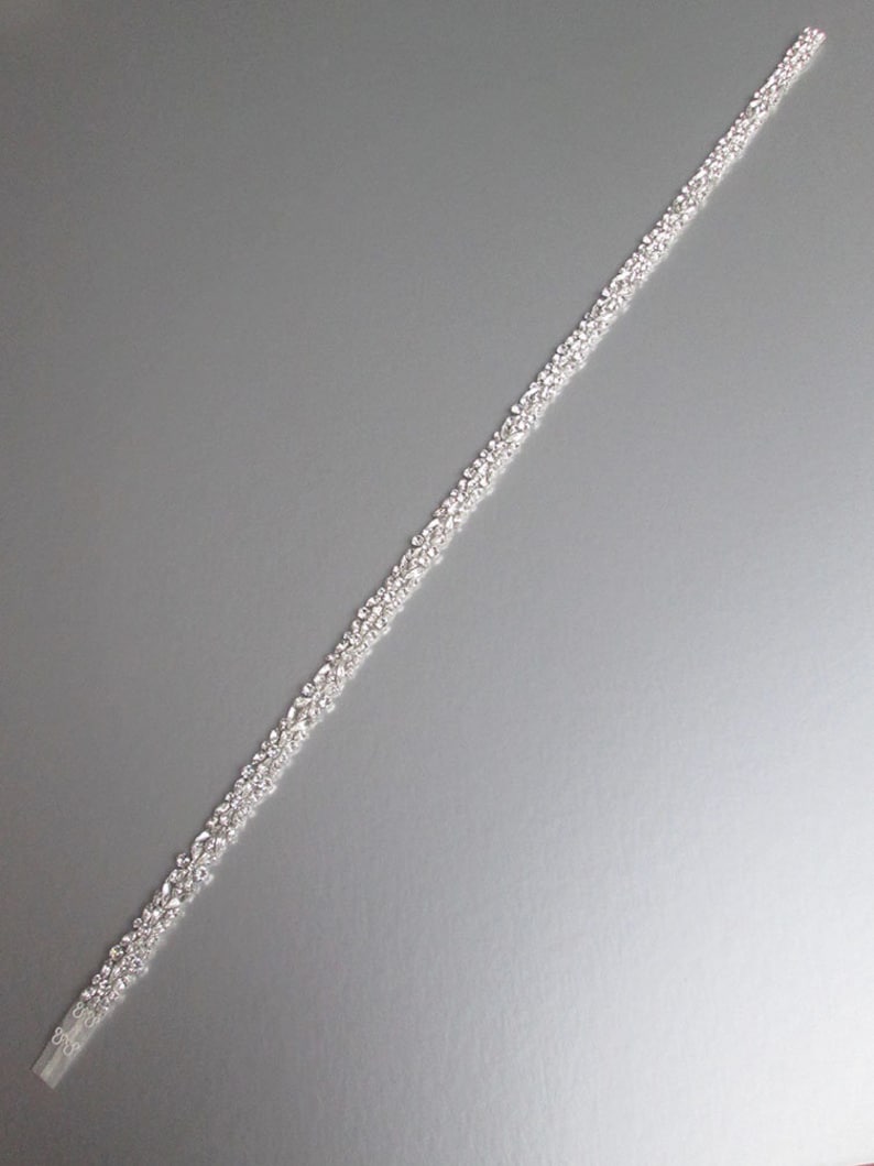 May include: A silver beaded trim with a clear backing. The trim is approximately 76 cm long and is perfect for adding a touch of sparkle to any project.