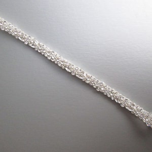 May include: A silver bridal sash with a row of clear rhinestones.