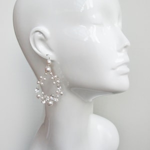 May include: Silver teardrop shaped earrings with white pearls and clear crystals.