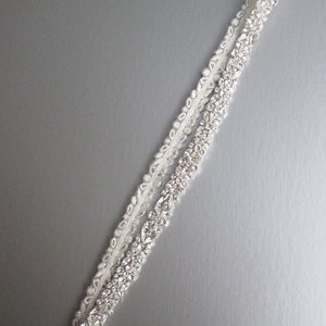 May include: A white satin bridal sash with a row of sparkling rhinestones.