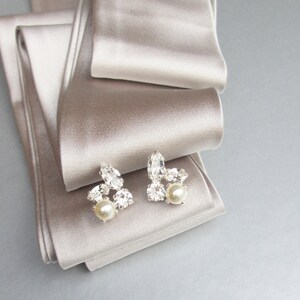 May include: A pair of silver earrings with a cluster of clear rhinestones and a single pearl on each earring.