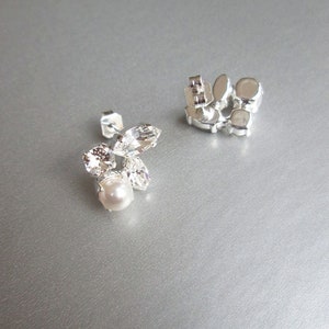 May include: A pair of silver earrings with clear crystal and pearl accents. The earrings have a post back fastening.