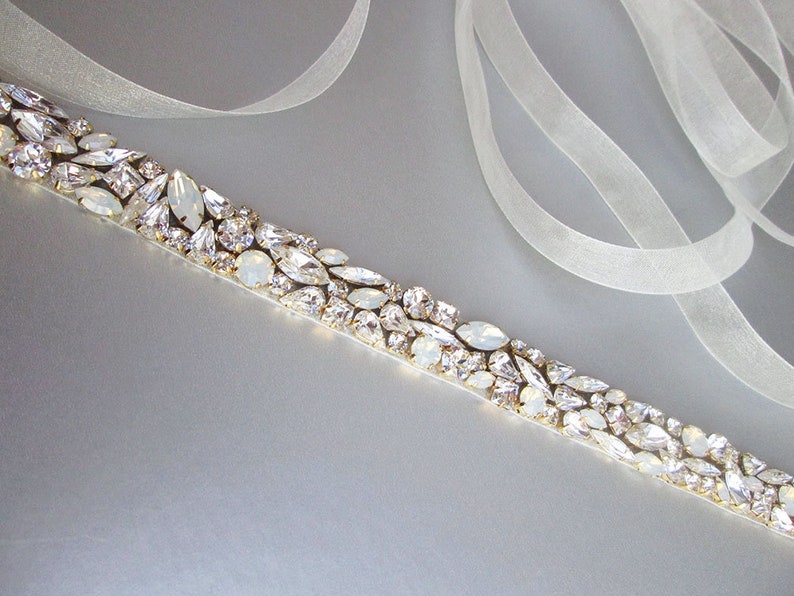 May include: A white satin ribbon with a row of clear and iridescent rhinestones, perfect for adding a touch of sparkle to a wedding dress or special occasion outfit.