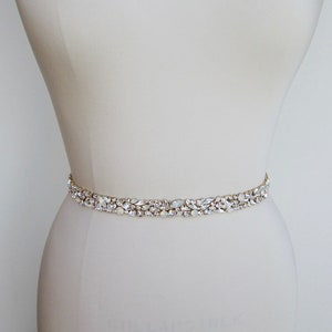 May include: A delicate bridal belt with a row of clear and iridescent crystals set in gold.
