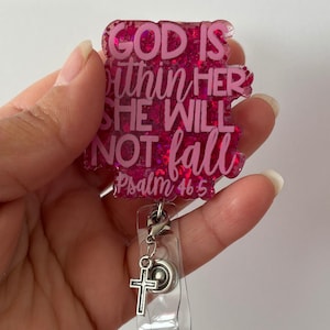 May include: A pink glitter badge reel with the text "GOD IS within HER SHE WILL NOT fall Psalm 46:5". The badge reel has a silver cross charm and a clear plastic holder.