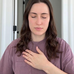 May include: A mauve-colored short-sleeved t-shirt featuring a crew neckline and a single chest pocket on the left side. The garment is constructed from a solid-colored fabric with visible stitching along the sleeves and the hemline of the shirt.