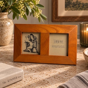 Puede incluir: Un marco de fotos doble rectangular de madera con un acabado marrón claro natural. El marco contiene dos imágenes, una con un boceto de dos figuras y la otra con el texto Umbra Twin Picture Frame 2,5 x 3 pulgadas (63 x 76 mm).