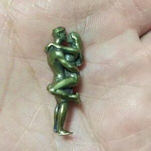 Puede incluir: Peque&ntilde;a escultura de color bronce que representa a una pareja abraz&aacute;ndose. El hombre sostiene a la mujer, que se inclina hacia atr&aacute;s. La escultura es detallada, mostrando los rasgos y la ropa de las figuras. Es probable que sea un objeto decorativo.