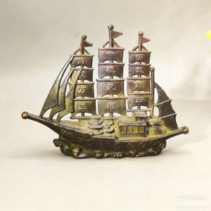 Puede incluir: Una taza de cerámica blanca con un asa negra y el texto "But First, Coffee" en un estilo manuscrito. La taza está sobre una superficie blanca. La taza mide aproximadamente 10 cm de alto.