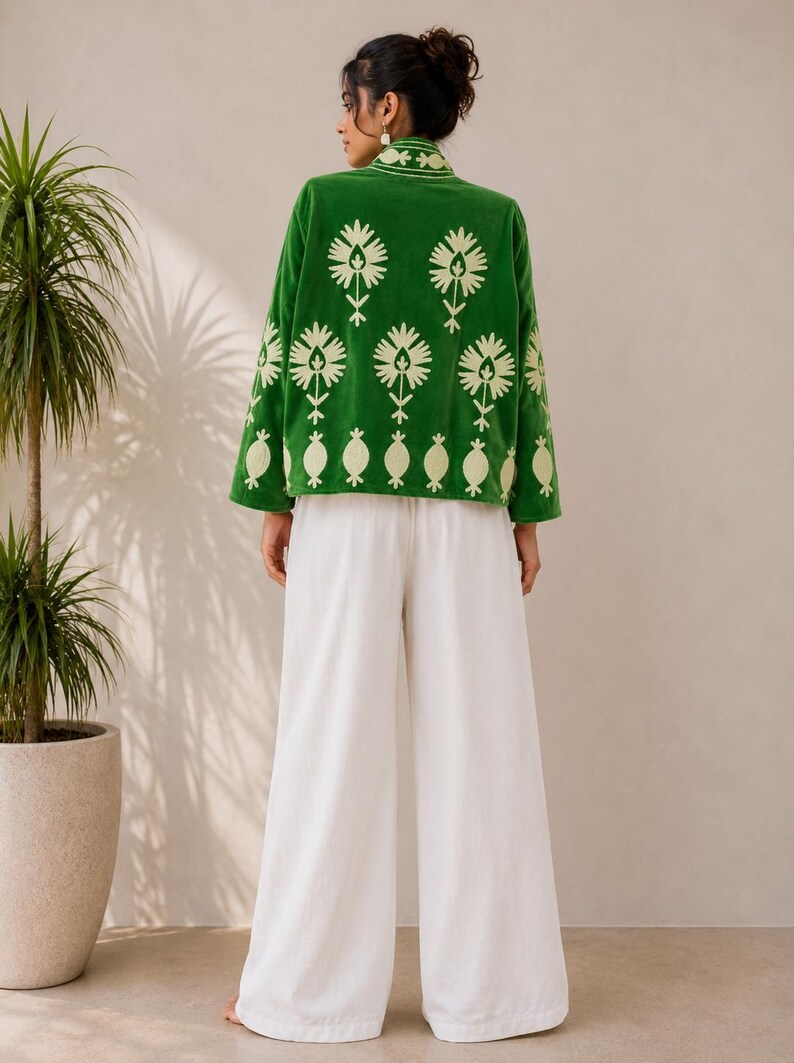 May include: A vibrant green jacket featuring a light cream-colored floral embroidery pattern on the back and sleeves, paired with loose-fitting white wide-leg trousers. The jacket has a high collar and long sleeves, creating a coordinated outfit.