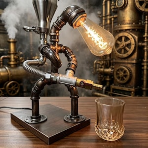 Puede incluir: Lámpara de escritorio de estilo steampunk hecha de tuberías y accesorios metálicos. La lámpara presenta una bombilla vintage estilo Edison, una parte superior en forma de embudo y una base de madera. Un vaso transparente está al lado de la lámpara. El fondo muestra maquinaria industrial.