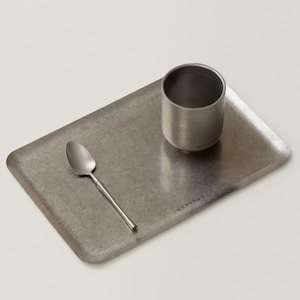 May include: A stainless steel serving tray with a small cup and spoon. The tray is rectangular with rounded corners. The cup is cylindrical, and the spoon has a long, thin handle. The word "WENSHUO" is printed on the tray.
