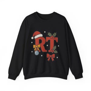 May include: Black crew neck sweatshirt with a festive design. The design features the letters "RT" in red, adorned with a Santa hat, holly, bows, and a Christmas ornament. The sweatshirt is a long-sleeved garment.