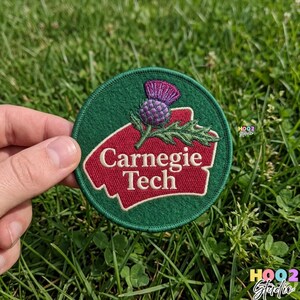 May include: A round, green embroidered patch with the words "Carnegie Tech" in white lettering on a red background. The patch features a purple thistle and green leaves.