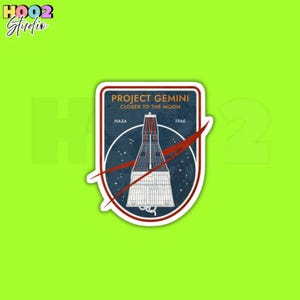 May include: A sticker featuring the Project Gemini mission patch. The patch includes the text "PROJECT GEMINI CLOSER TO THE MOON" and "NASA 1966". The design features a rocket and a red streak across a blue background.
