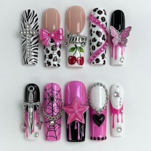 May include: A set of ten long, artificial nails with various designs. The designs include zebra print, bows, leopard spots, cherries with the word "Juicy", pink rhinestones, butterflies, spiderwebs, stars, hearts, and dripping paint.
