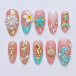 Può includere: Un set di dieci unghie finte a tema estivo. Ogni unghia presenta un design diverso, tra cui conchiglie, stelle marine, cavallucci marini e accenti floreali, nelle tonalità del rosa, dell'oro e del turchese. Alcune unghie hanno abbellimenti di perle.