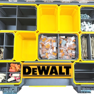 May include: A DeWalt organizer case featuring a black and yellow plastic frame with multiple removable compartments. The interior contains various hardware items including metal screws, orange wire connectors, and clear electrical wire terminals.