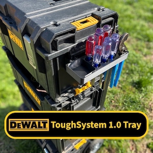 May include: Black and yellow DEWALT ToughSystem 1.0 Tray toolbox with a variety of tools, including screwdrivers and pliers. The toolbox is stacked on top of other toolboxes. The text "DEWALT ToughSystem 1.0 Tray" is displayed in a yellow banner.