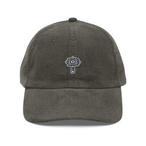 Peut inclure: Casquette de baseball en velours côtelé vert olive avec un petit motif de marteau brodé sur le devant. La casquette a une visière incurvée et une sangle réglable à l'arrière.