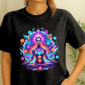 May include: Black t-shirt featuring a vibrant illustration of a person meditating in the lotus position. The design includes colorful energy fields and chakra symbols in shades of blue, purple, orange, and pink. The artwork is centered on the shirt.