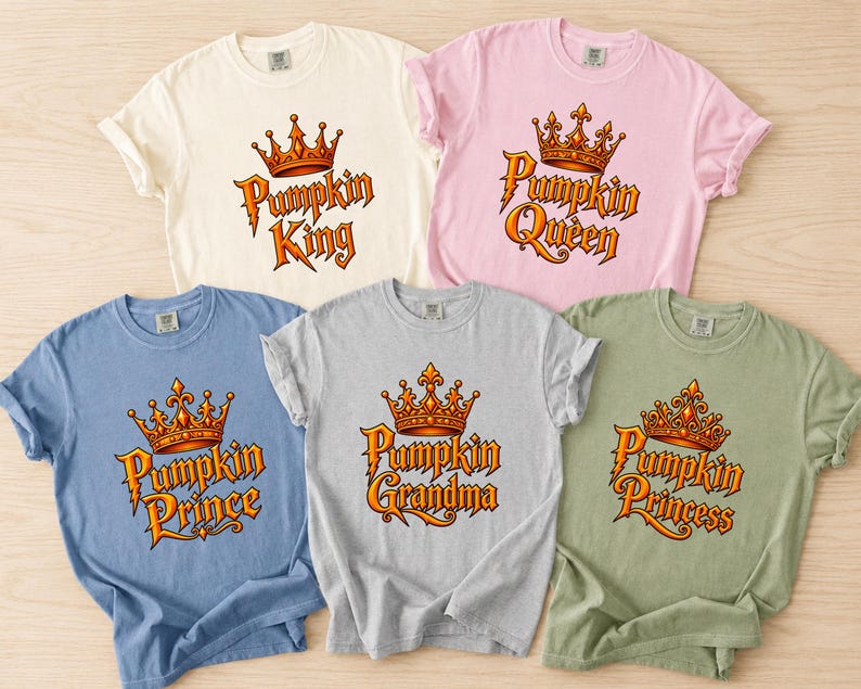 May include: Five short-sleeved crew neck t-shirts in cream, light pink, blue, gray, and sage green. Each shirt features a graphic of an orange crown above text reading Pumpkin King, Pumpkin Queen, Pumpkin Prince, Pumpkin Grandma, or Pumpkin Princess.